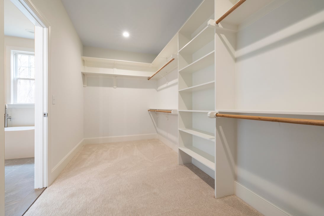 A Carpeted Walk-in Empty Closet with White Theme